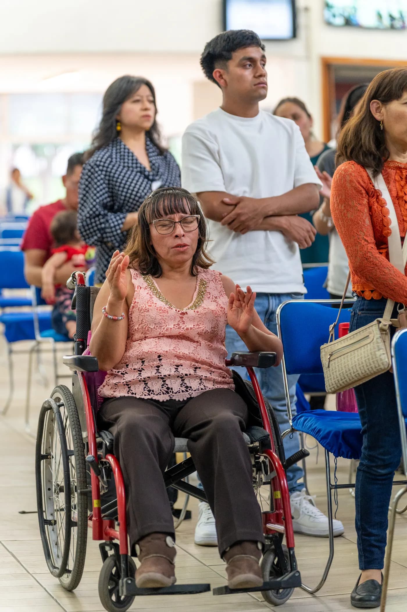 A woman using a wheelchair worshipping alongside her church community